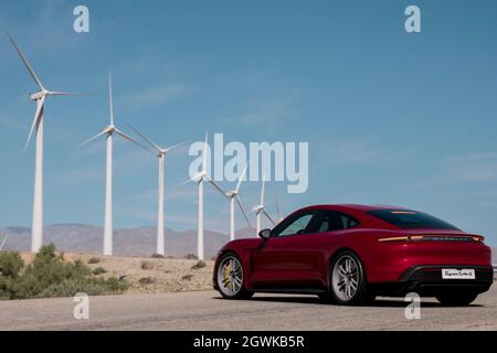 Antalya, Türkei 1. Oktober 2021: Ein kirschmetallisches, elektrisches Modell, Porsche Taycan Turbo S vor Windkraftanlagen. Stockfoto