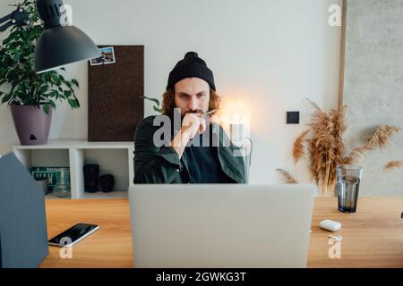Online-Schulungen. Studenten studieren, während sie Online-Vorlesungen mit einem Laptop hören. Bärtiger Hipster bei der Hausarbeit Stockfoto
