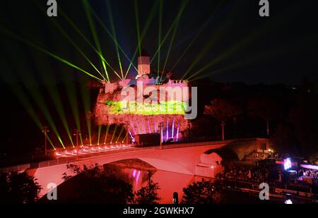 03. Oktober 2021, Sachsen-Anhalt, Halle (Saale): Die Ruinen von Schloss Giebichenstein erstrahlen in den Farben der Bundesflagge. Zum Abschluss der zentralen Feierlichkeiten zum Tag der Deutschen Einheit findet in der Burgruine eine Multimedia- und Drohnenshow statt. Foto: Hendrik Schmidt/dpa-Zentralbild/dpa Stockfoto