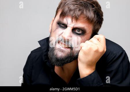 Porträt eines bärtigen Mannes mit untotem Make-up, der seine Hand in der Nähe seines Kopfes hält Stockfoto