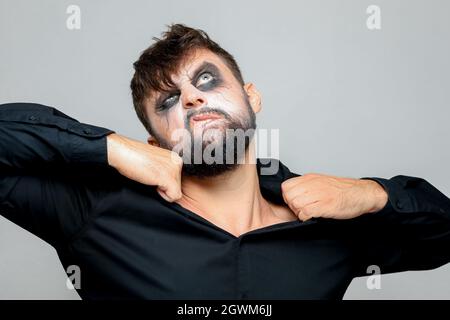 Untoten-Stil Make-up auf einem reichen Mann, der an den Kragen seines Hemdes mit seinen Händen hält Stockfoto