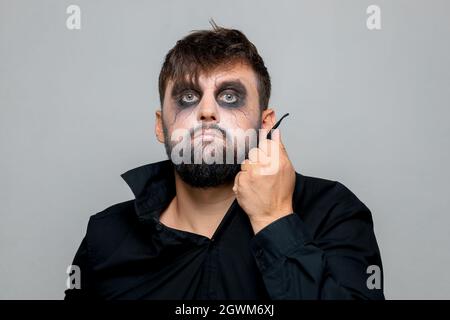 Untoten-Stil Make-up auf einem reichen Mann, der an den Kragen seines Hemdes mit seinen Händen hält Stockfoto