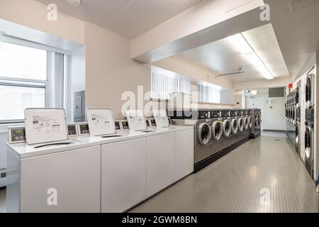 Ein Hochhauswaschsalon in der Innenstadt mit Schnellwaschmaschinen und Trocknern, die in Reihen angeordnet sind. Stockfoto