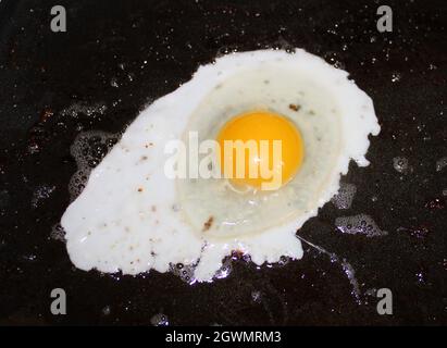 Frisch geknacktes Ei beginnt zu kochen. Stockfoto