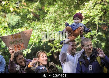 London, Großbritannien. Oktober 2021. Ein Mann hebt ein kleines Kind vorsichtig in die Luft, während eine Frau in der Gruppe ein Schild mit dem Namen „Run Daty Fox“ hochhält, das den Jungen zu einem „Baby Fox“ machen könnte. Zuschauer beobachten den Virgin London Marathon 2021. Kredit: Imageplotter/Alamy Live Nachrichten Stockfoto