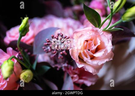 Blumenstrauß aus Rosen und Blumen aus der Nähe auf schwarzem Hintergrund mit geringer Schärfentiefe und verschwommenem Hintergrund Stockfoto