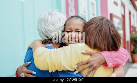 Multirassische ältere Frauen haben Spaß zusammen Umarmung im Freien in der Stadt - Fokus auf afrikanische weibliche Gesicht Stockfoto