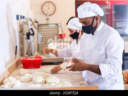 Hispanischer Bäcker knetet und bildet Teig zum Backen von Brot Stockfoto