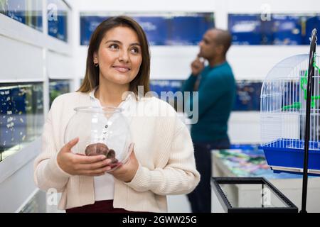 Positive Frau, die Aquarienfische im Laden wählt Stockfoto