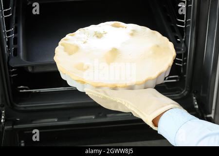 Frau, die ungekochte Hühnertopf-Pie mit Gemüse in den Ofen legte Stockfoto