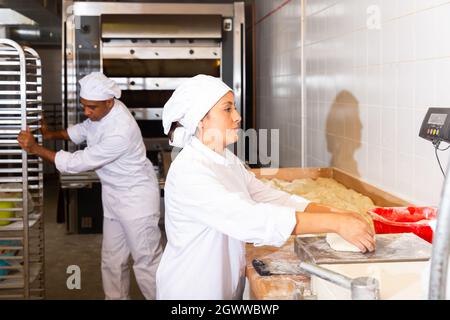 Baker wiegt Teig auf Schuppen in der Bäckerei Stockfoto