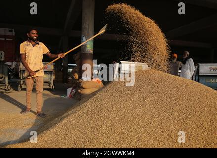 Punjab. Oktober 2021. Arbeiter winkten Getreide auf einem lokalen Getreidemarkt im Distrikt Amritsar im nördlichen indischen Bundesstaat Punjab, 3. Oktober 2021. Quelle: Str/Xinhua/Alamy Live News Stockfoto