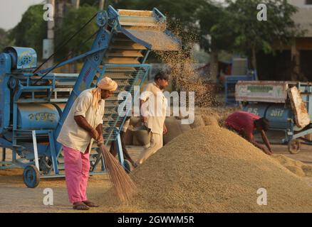 Punjab. Oktober 2021. Arbeiter winkten Getreide auf einem lokalen Getreidemarkt im Distrikt Amritsar im nördlichen indischen Bundesstaat Punjab, 3. Oktober 2021. Quelle: Str/Xinhua/Alamy Live News Stockfoto