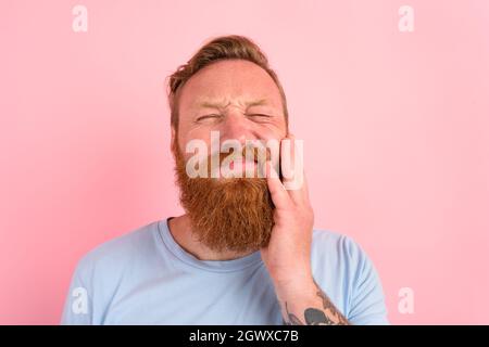Glücklicher Mann mit hellblauem T-Shirt hat Schmerzen in den Zähnen Stockfoto