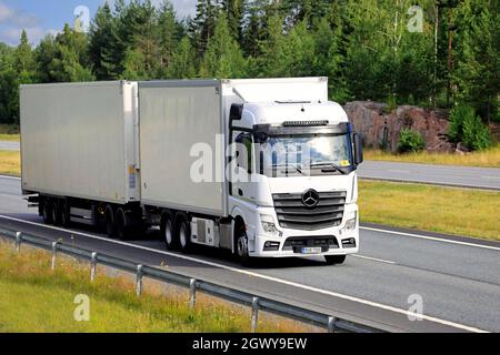 Weißer Mercedes-Benz Actros Lkw transportiert Güter im FRC-Anhänger an einem schönen Sommertag entlang der Autobahn. Salo, Finnland. 9. Juli 2021. Stockfoto