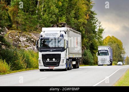 An einem bewölkten Herbsttag transportieren zwei weiße Volvo Sattelschlepper Güter auf der Autobahn 52. Salo, Finnland. 23. September 2021. Stockfoto