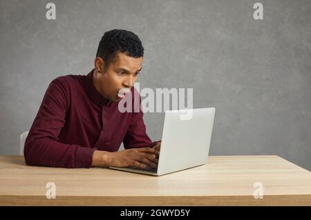 Junger afroamerikanischer Mann in Schwierigkeiten wegen Computerfehler oder Software-Problem auf Laptop Stockfoto