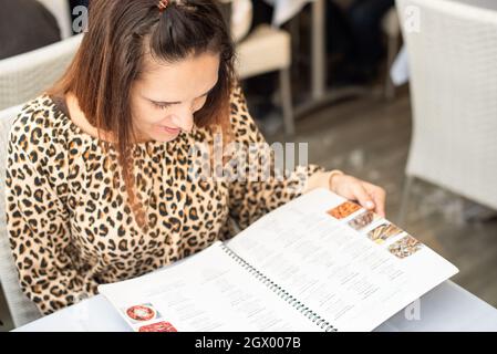 Frau in einem Restaurant, die an der Speisekarte liest Stockfoto