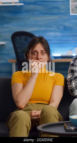 POV von schockierten interracial paar schaurig Film im Fernsehen zu Hause. Multiethnische Ehemann und Ehefrau haben Angst und verdecken die Augen, während sie die Kamera im Wohnzimmer betrachten Stockfoto