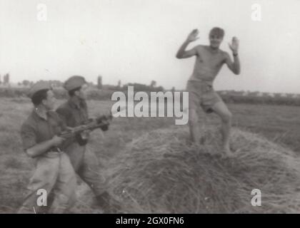 Vintage / Retro Armee / Militär PPSh-41 Serie 3. Zwei Soldaten werden auf dem Heurick gefangen, die möglicherweise in die freie Welt (außerhalb des Eisernen Vorhangs) fliehen wollten und gegen ihn die sowjetische Maschinenpistole (Papascha-Entwurf von Georgy Shpagin) in den 1950er Jahren auf dem Feld halten. Sie kommen aus Osteuropa, möglicherweise aus Ungarn. HE PPSh-41 war von 1941-1960 im Dienst. Quelle: Originalfoto. Stockfoto