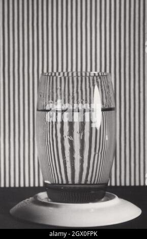 Super seltenes Vintage-Kunstfoto aus den 1960er oder 1970er Jahren. Dieses monochrome Foto zeigt ein fast voll Glas mit Wasser. Durch das Glas zu sehen, ist die Rückseite ein wenig schillernd und größer als sie tatsächlich ist. Dies ist ein sehr kreatives und einzigartiges Künstlerfoto. Quelle: Originalfoto Stockfoto