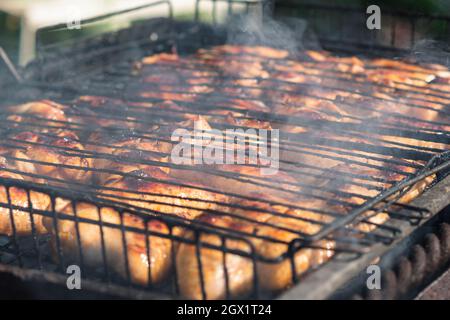 Kochen Hähnchenflügel auf dem Grill auf dem Grill. Rauch steigt aus den Kohlen auf. Selektiver Fokus. Backyard-Kochkonzept Stockfoto