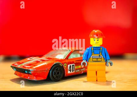 POZNAN, POLEN - 15. Feb 2019: Ein Lego-Spielzeug eines Bauarbeiters, der neben seinem roten Ferrari GTO-Rennwagen steht Stockfoto
