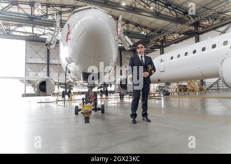 Professioneller Pilot, der eine Mütze in den Händen hält und zur Seite schaut Stockfoto