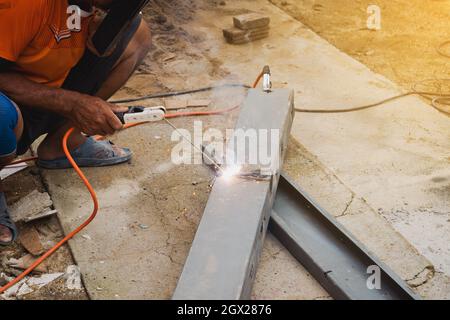 Mann Schweißer, der eine Metalltreppenkonstruktion in einem Wohngebäude mit einer Schweißmaschine macht. Stockfoto