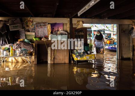 Nonthaburi, Thailand. Oktober 2021. Eine Frau steht in einem überfluteten Bereich. Thailand ist aufgrund der starken Regenfälle, der Gezeitenwelle und der Wasserabflüsse vom Chao Phraya-Staudamm nach dem Sturm von Dianmu im Land mit einer Sturmflut konfrontiert. Viele Bewohner sind jedes Jahr mit Überschwemmungen konfrontiert, aber in diesem Jahr stieg der Wasserstand sofort an und verursachte mehr Schäden als üblich. Kredit: SOPA Images Limited/Alamy Live Nachrichten Stockfoto