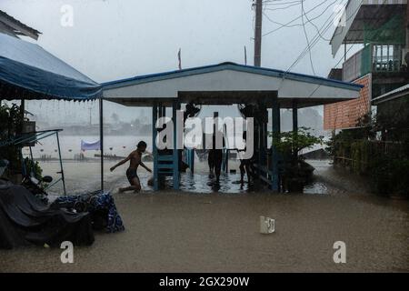 Nonthaburi, Thailand. Oktober 2021. Kinder werden bei starken Regenfällen beim Spielen beobachtet. Thailand ist aufgrund der starken Regenfälle, der Gezeitenwelle und der Wasserabflüsse vom Chao Phraya-Staudamm nach dem Sturm von Dianmu im Land mit einer Sturmflut konfrontiert. Viele Bewohner sind jedes Jahr mit Überschwemmungen konfrontiert, aber in diesem Jahr stieg der Wasserstand sofort an und verursachte mehr Schäden als üblich. Kredit: SOPA Images Limited/Alamy Live Nachrichten Stockfoto