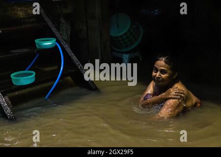 Nonthaburi, Thailand. Oktober 2021. Eine Frau wird im Flutwasser baden gesehen. Thailand ist aufgrund der starken Regenfälle, der Gezeitenwelle und der Wasserabflüsse vom Chao Phraya-Staudamm nach dem Sturm von Dianmu im Land mit einer Sturmflut konfrontiert. Viele Bewohner sind jedes Jahr mit Überschwemmungen konfrontiert, aber in diesem Jahr stieg der Wasserstand sofort an und verursachte mehr Schäden als üblich. Kredit: SOPA Images Limited/Alamy Live Nachrichten Stockfoto