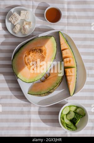 Frische Melonen in Scheiben geschnitten auf Tischdecke. Freier Speicherplatz für Text. Draufsicht. Melone aus japanischen Melonen, Honigmelone oder Cantaloupe Cucumis melo auf Holzlasche geschnitten Stockfoto