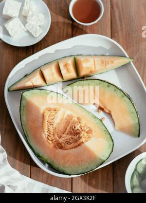 Frische Melonen in Scheiben auf Holztisch. Freier Speicherplatz für Text. Draufsicht. Melone aus japanischen Melonen, Honigmelone oder Cantaloupe Cucumis melo auf Holz geschnitten Stockfoto