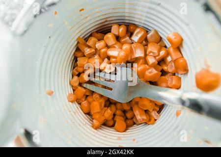 Mais aus der Dose in einem Glas mit einer Gabel aus der Nähe. Stockfoto