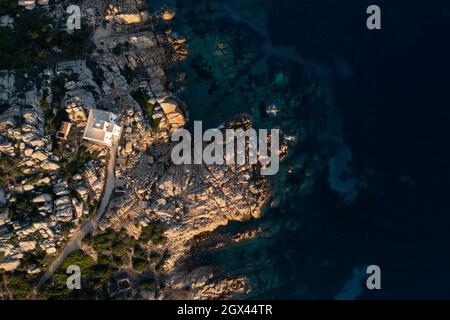 Blick von oben, atemberaubende Luftaufnahme der Vedetta di Punta Sardegna, einem weißen Leuchtturm an einer granitischen, felsigen Küste. Stockfoto