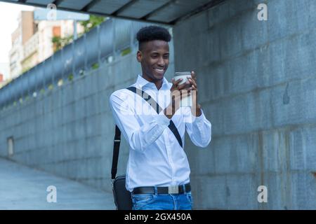 Portrait junger afroamerikanischer Geschäftsmann, der sich auf der Straße mit einem Glas Kaffee die Hände wärmte Stockfoto