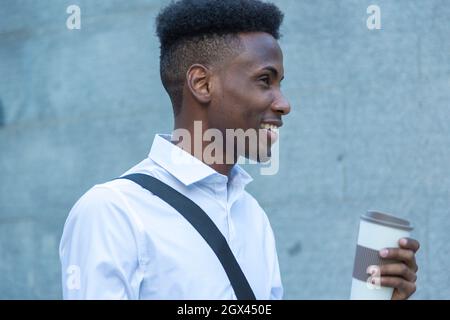 Portrait junger afroamerikanischer Geschäftsmann mit einem Glas Kaffee in der Hand auf der Straße Stockfoto