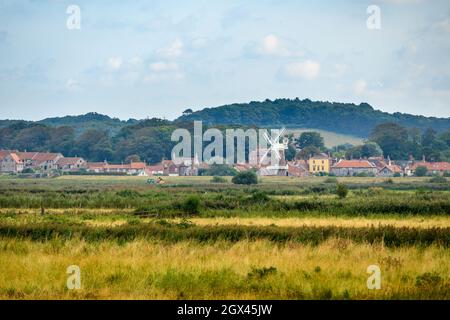 Blick auf Cley neben dem Sea Village mit Cley Windmill vom Wanderweg in Blakeney Freshes, Norfolk, England. Stockfoto