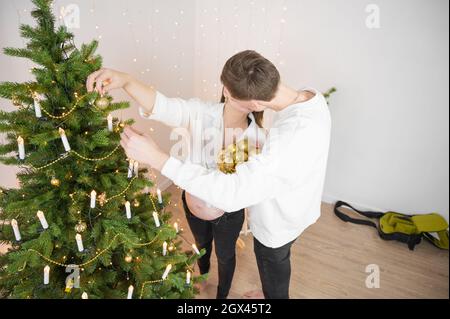 Glückliches Paar küsst sich in der Nähe von Weihnachtsbaum zu Hause Stockfoto