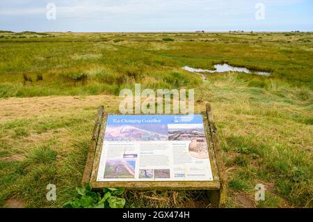 „Die Sich Verändernde Küste.“ Informationstafel über das Sumpfgebiet in und um Blakeney Freshes und Blakeney National Nature Reserve, Norfolk, England. Stockfoto