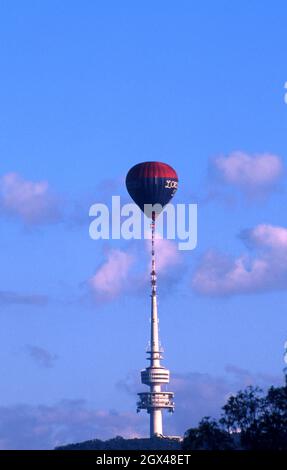 Ein Heißluftballon fliegt direkt über den Telstra Tower auf dem Black Mountain während der Canberra Balloon Spectacular, die jährlich stattfindet. HANDELN. Stockfoto