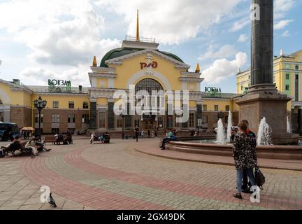 Die Menschen ruhen am Brunnen auf dem Bahnhofsplatz vor dem Hauptbahnhof mit dem russischen Eisenbahnlogo auf Russisch an der Fassade Stockfoto