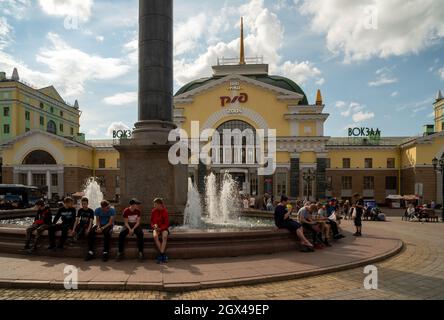 An einem sonnigen Sommertag ruhen sich die Menschen am Brunnen auf dem Bahnhofsplatz vor dem Hauptbahnhof der Stadt aus. Stockfoto