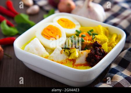 „ Lontong Ketupat / Lontong Kupat “ oder Reiskuchen mit Kokosnuss-Soße mit Tumeric, Chili und Gemüse. Ein berühmtes malaysisches und indonesisches Essen. Stockfoto