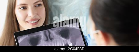 Der Zahnarztarzt untersucht die Röntgenaufnahme des weiblichen Kiefers Stockfoto