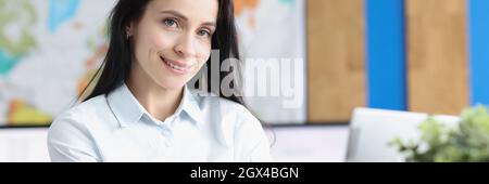 Eine junge lächelnde Geschäftsfrau sitzt im Büro am Laptop Stockfoto