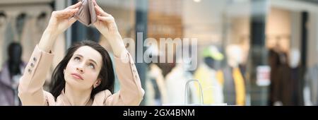 Junge Frau schaut in eine leere Brieftasche im Einkaufszentrum Stockfoto