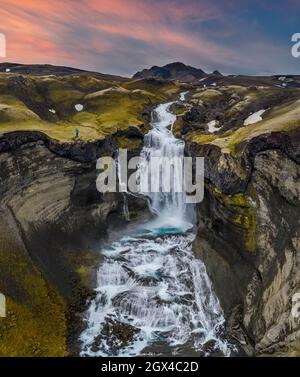 Person am Ofaerufoss Wasserfall im Sommer bei Sonnenuntergang, Eldgja, Highland, Island, Nordeuropa Stockfoto