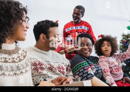 afroamerikanische Familie lächelt, während sie im Wohnzimmer spricht Stockfoto